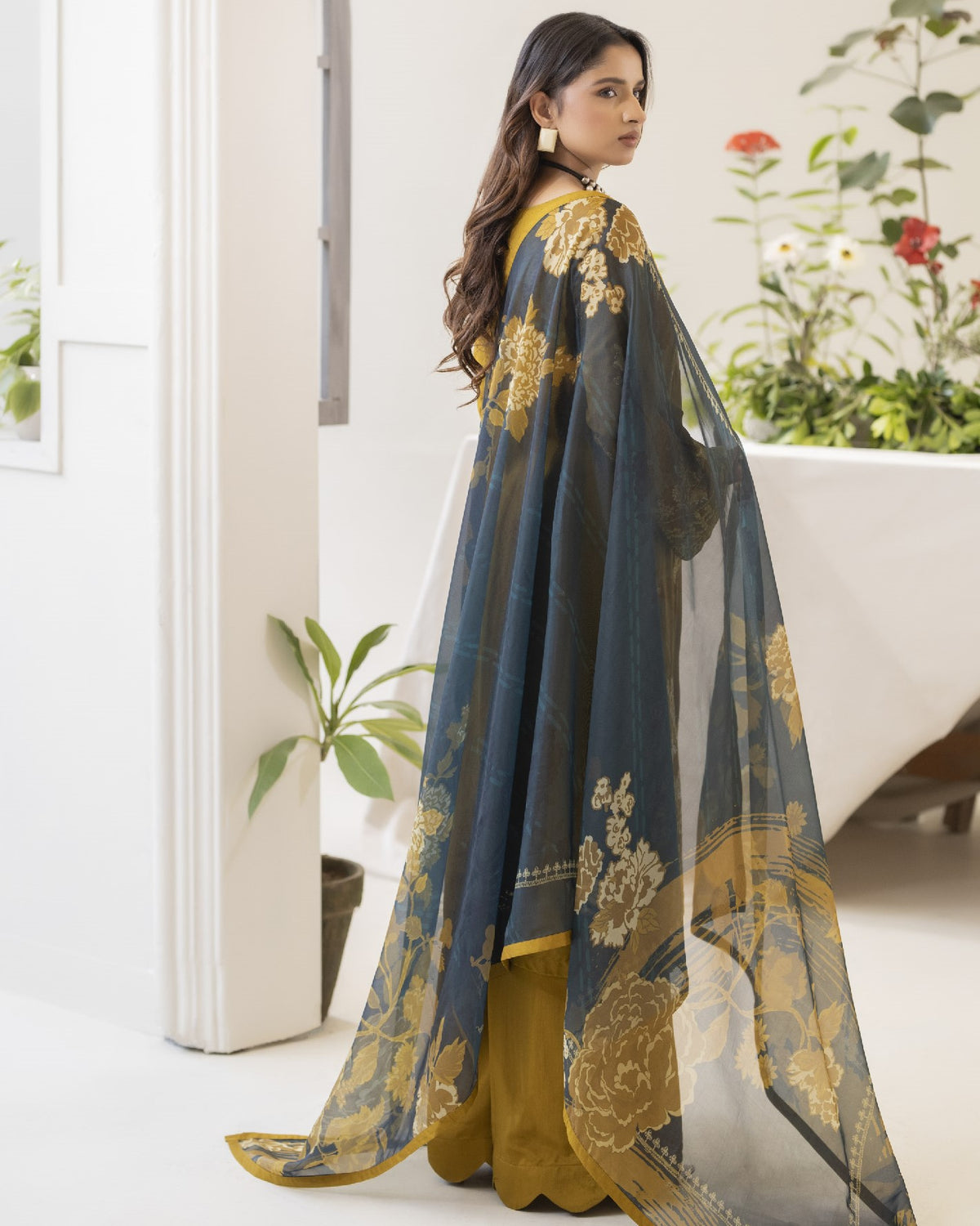 Woman wearing a traditional outfit with floral patterns in a home setting