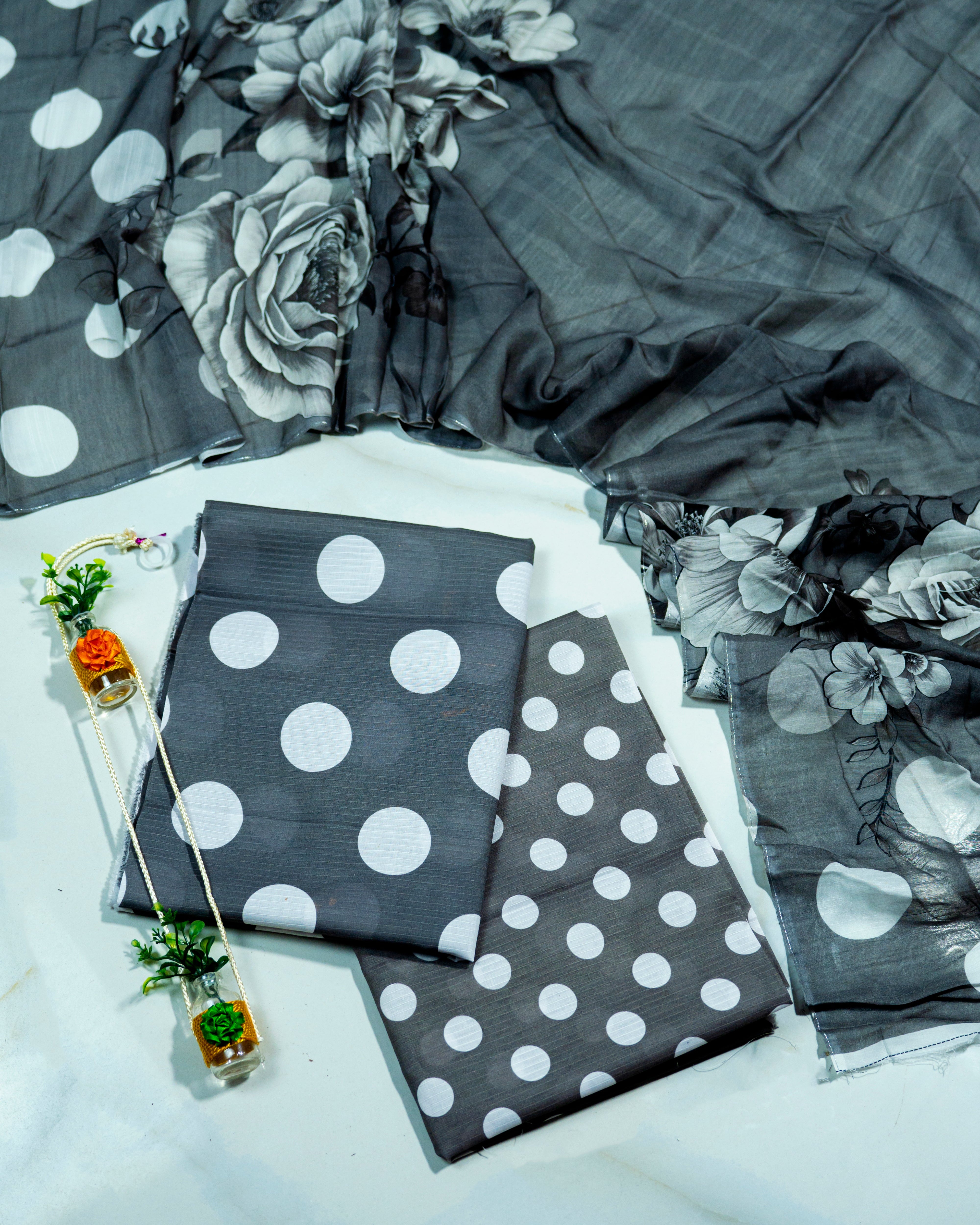 Gray and white polka dot fabric with floral pattern on a white surface