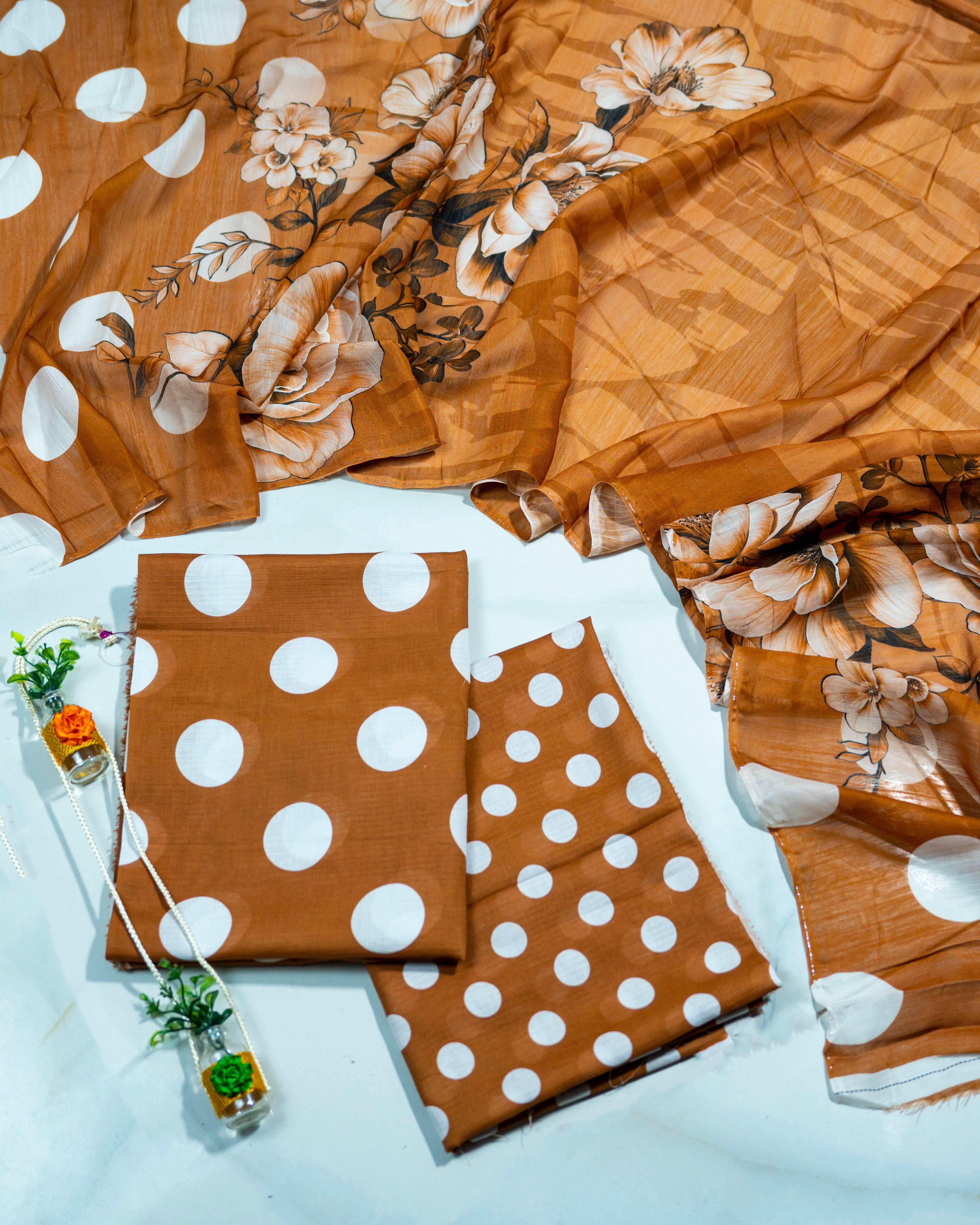 Brown fabric with white polka dots and floral patterns on a light gray background