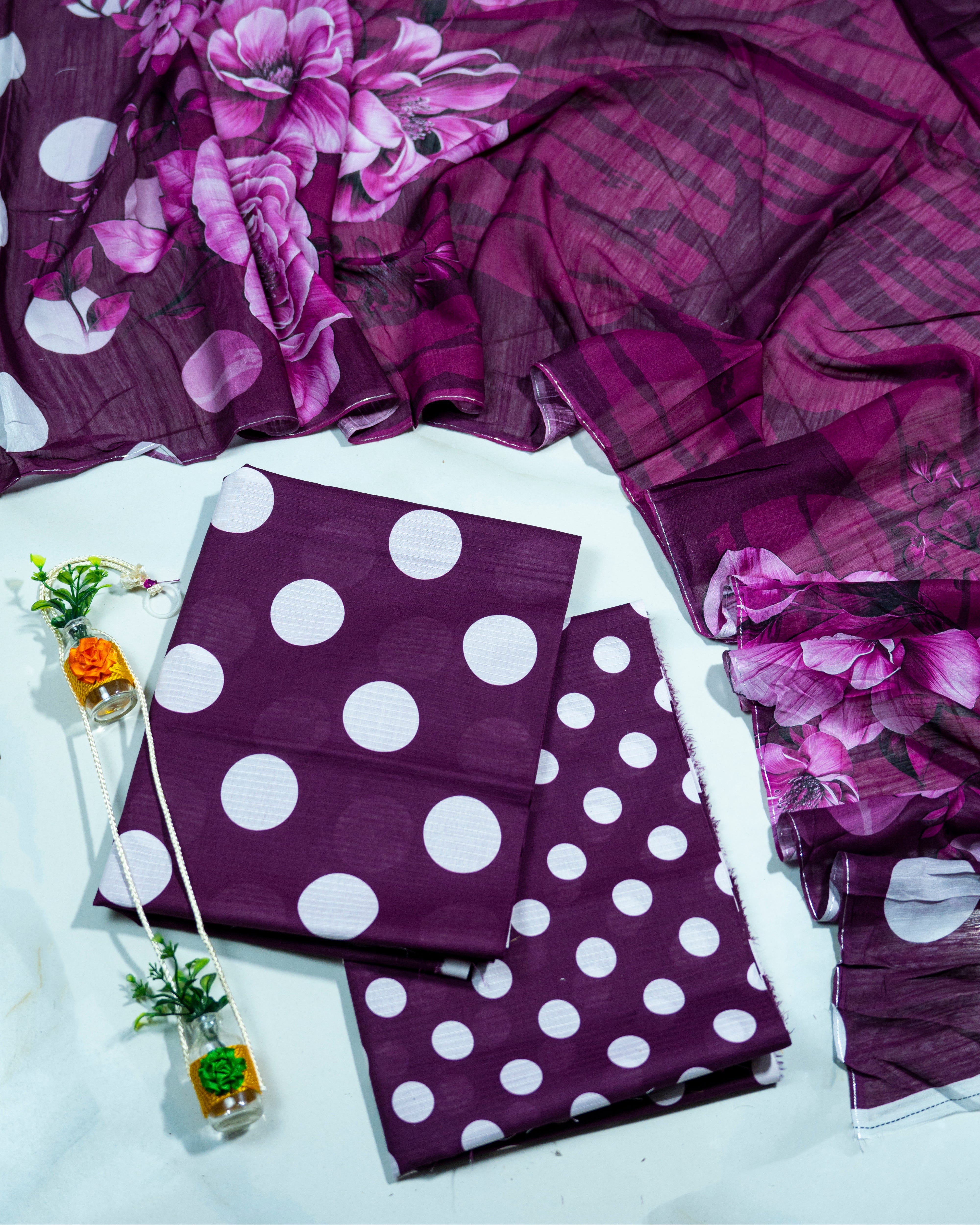 Purple fabric with floral patterns and white polka dots on a white background