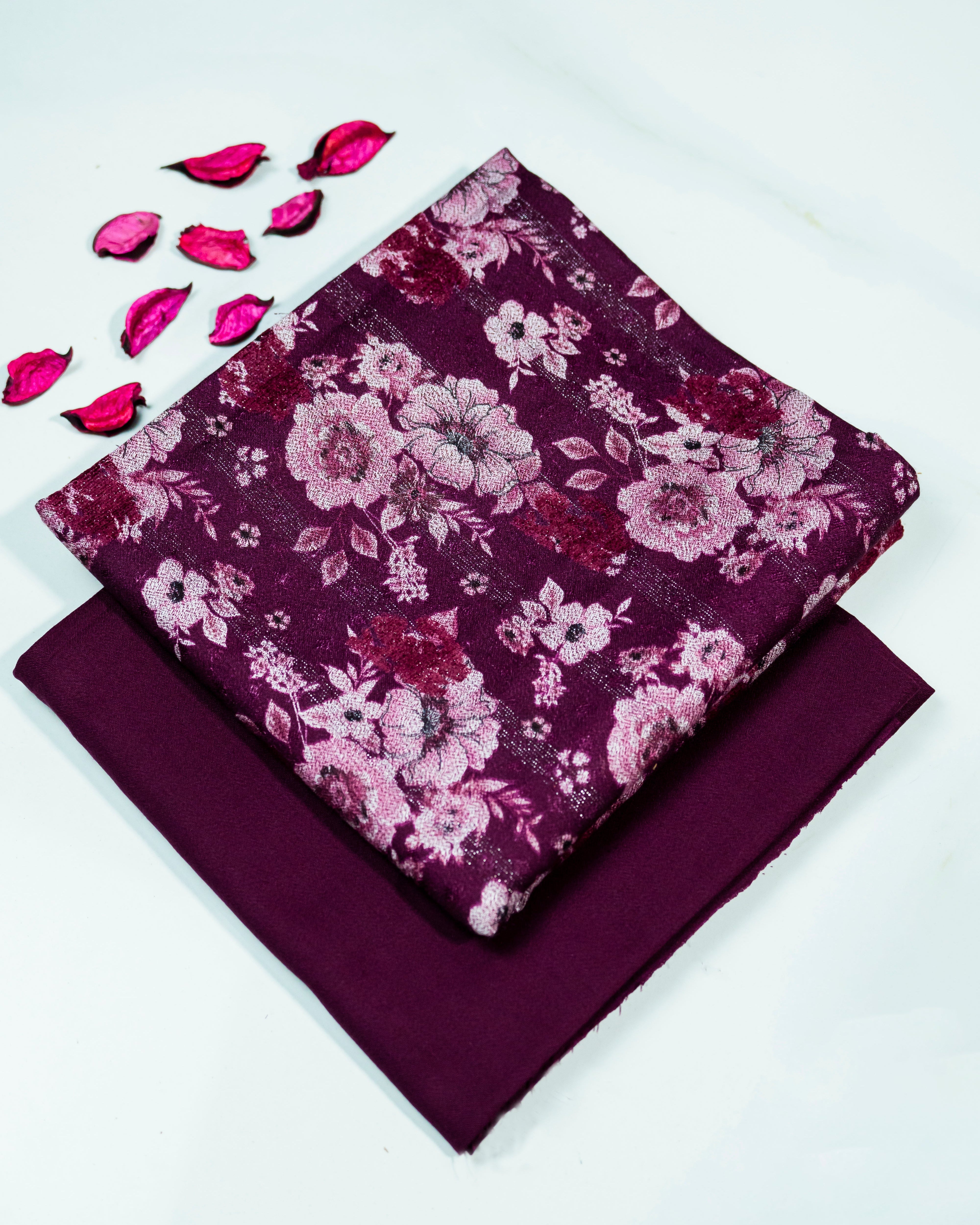 Purple fabric with floral pattern and pink petals on a white background