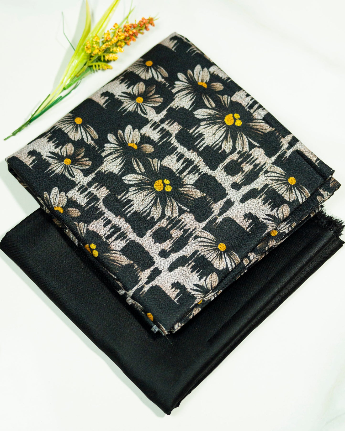 Floral fabric with yellow centers on a black background, folded and displayed.