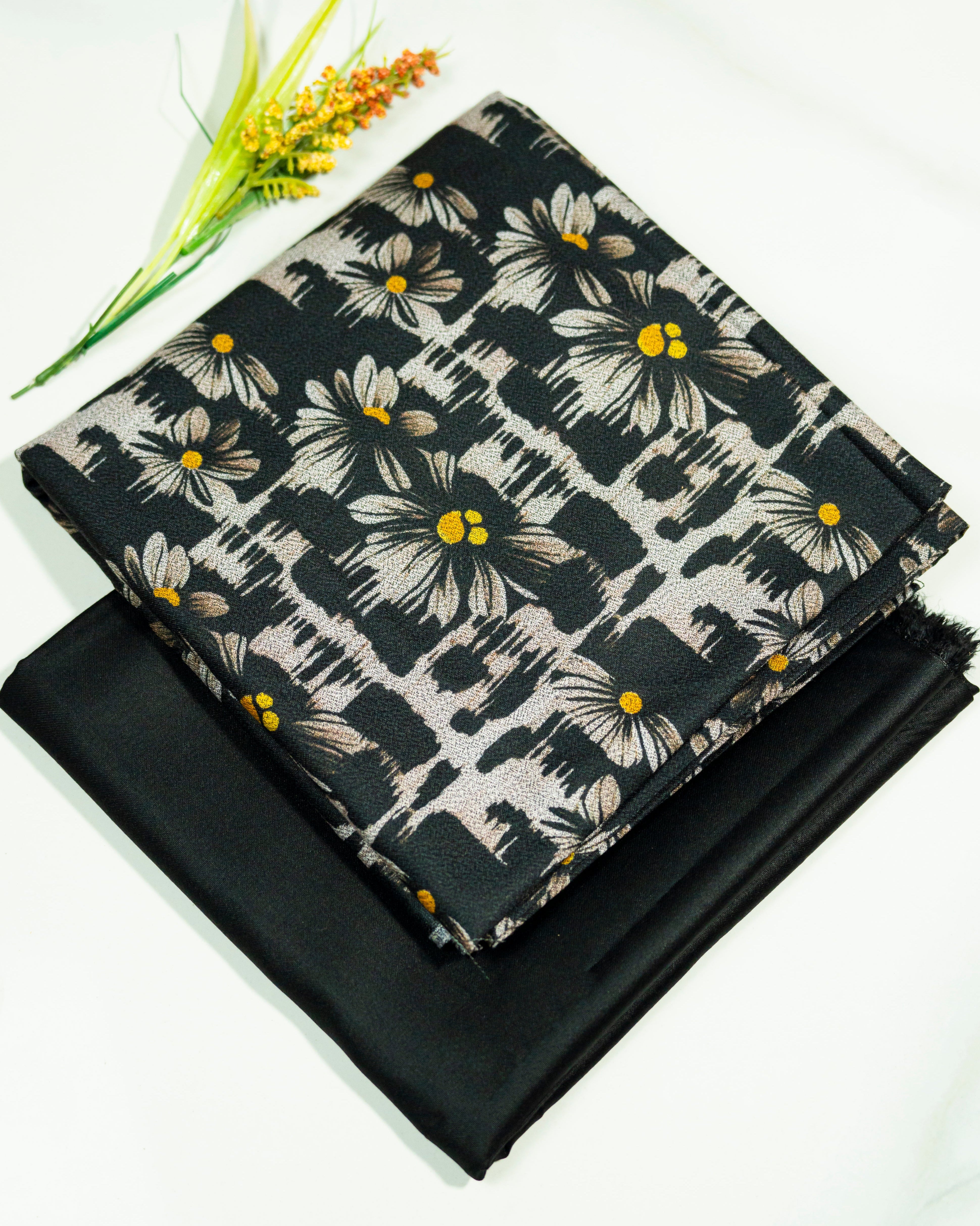 Floral fabric with yellow centers on a black background, folded and displayed.