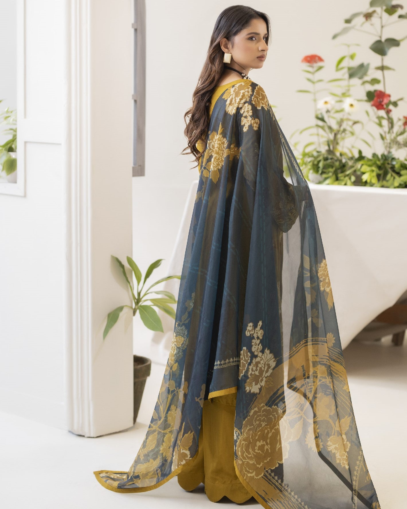 Woman wearing a traditional outfit with floral patterns in a home setting