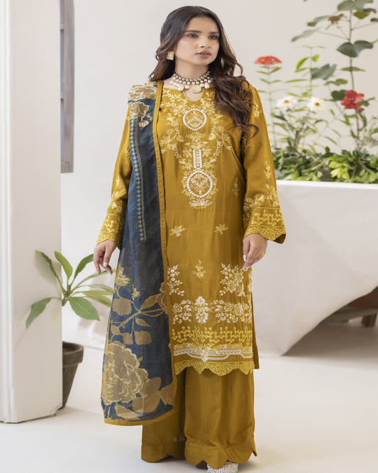 A woman wearing a yellow embroidered shirt with floral patterns, a blue dupatta, and matching trousers.