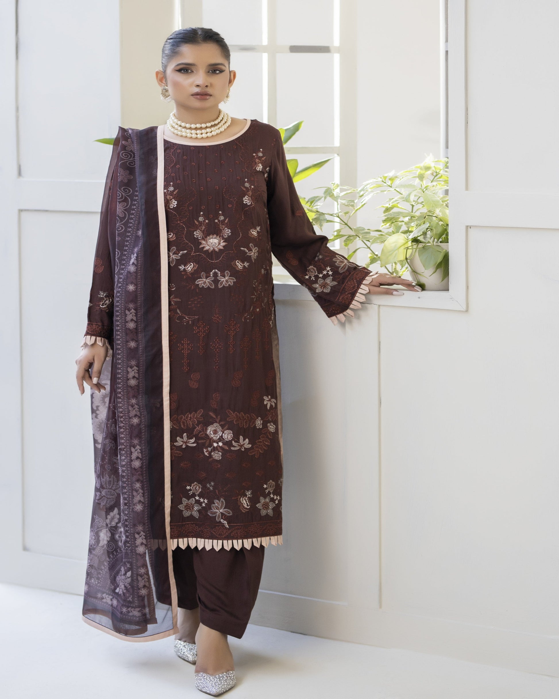 A woman wearing a maroon color embroidered shirt with digital printed silk dupatta and matching trousers.