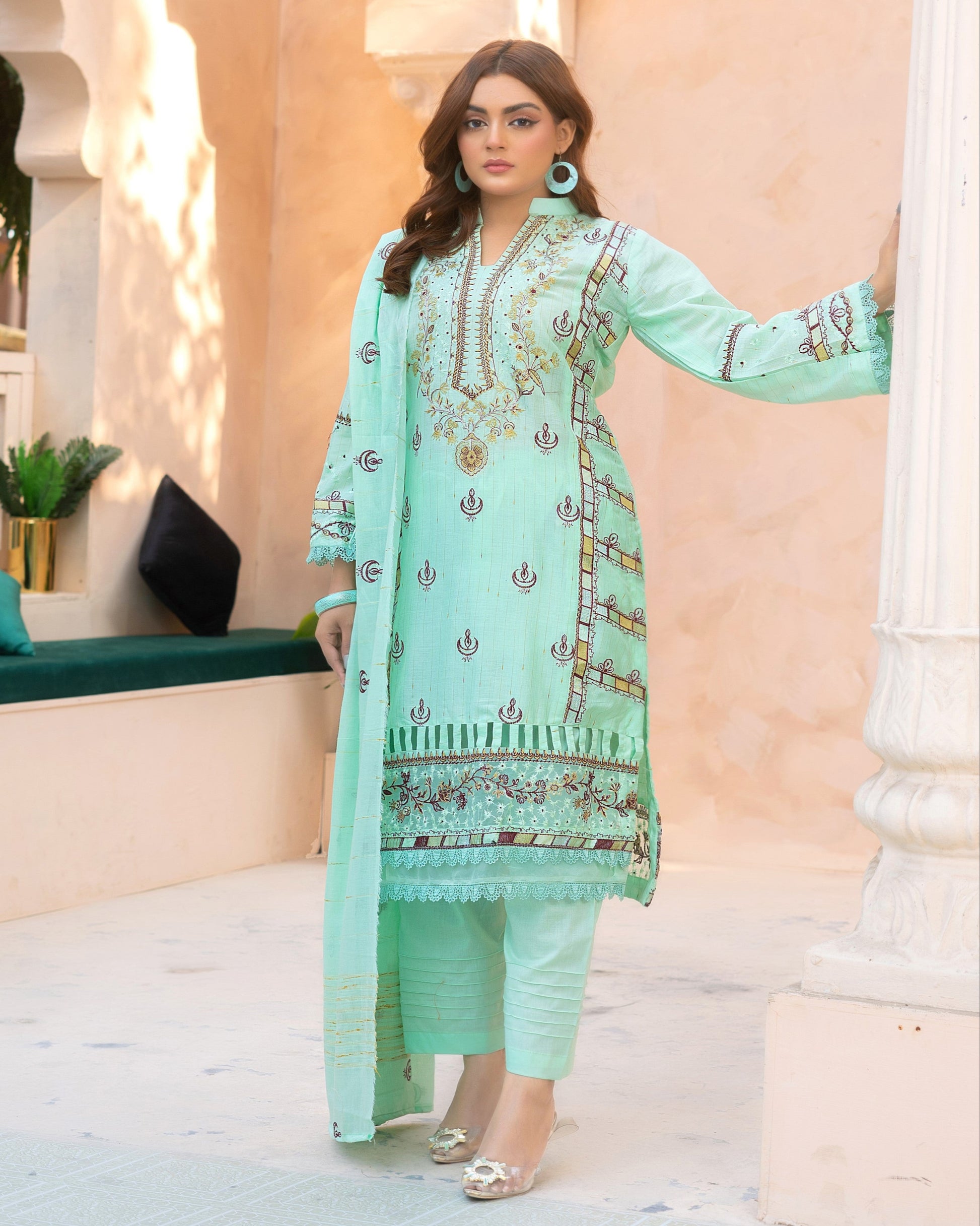 A woman wearing a green traditional outfit with floral embroidery and a dupatta.
