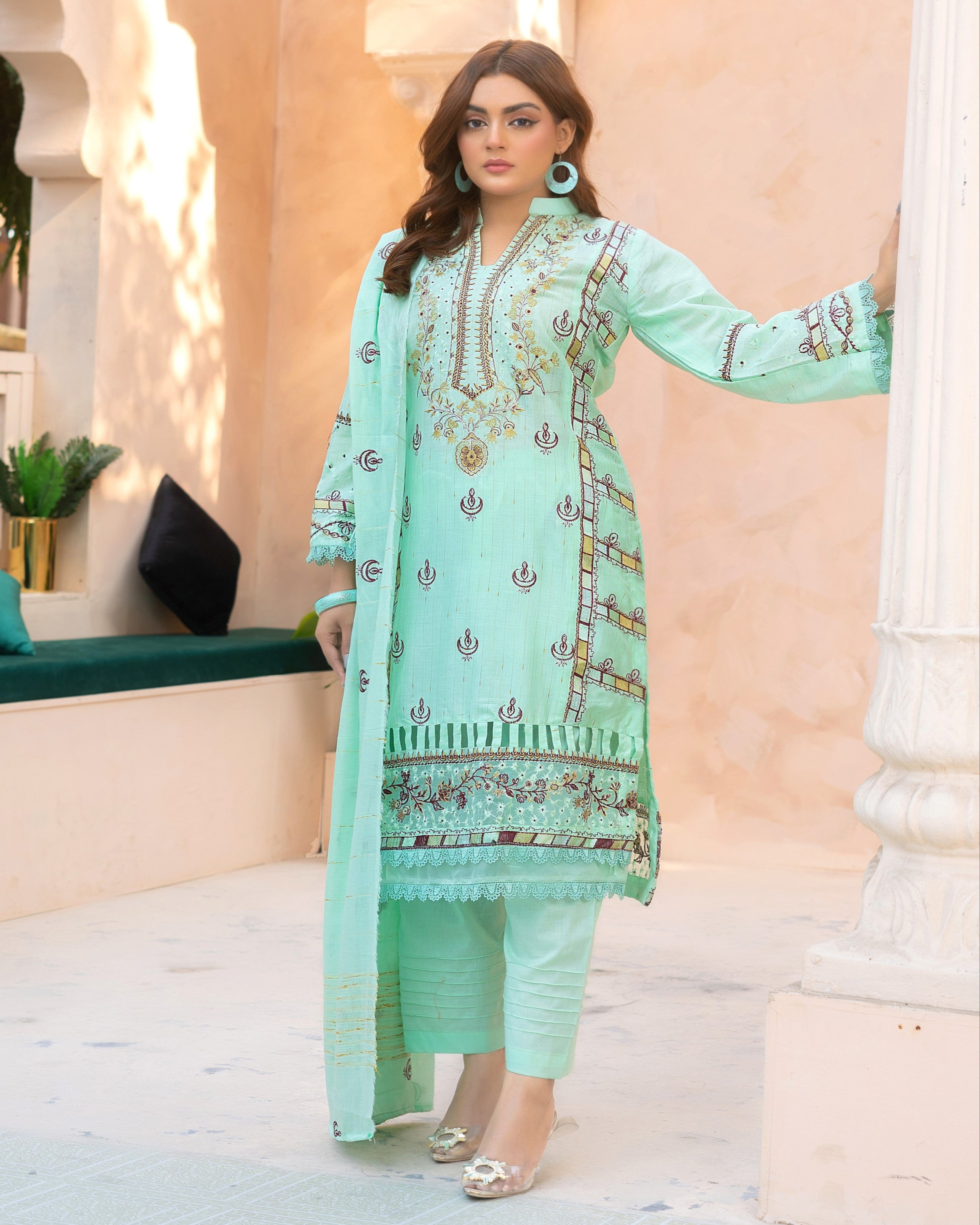 A woman wearing a green traditional outfit with floral embroidery and a dupatta.