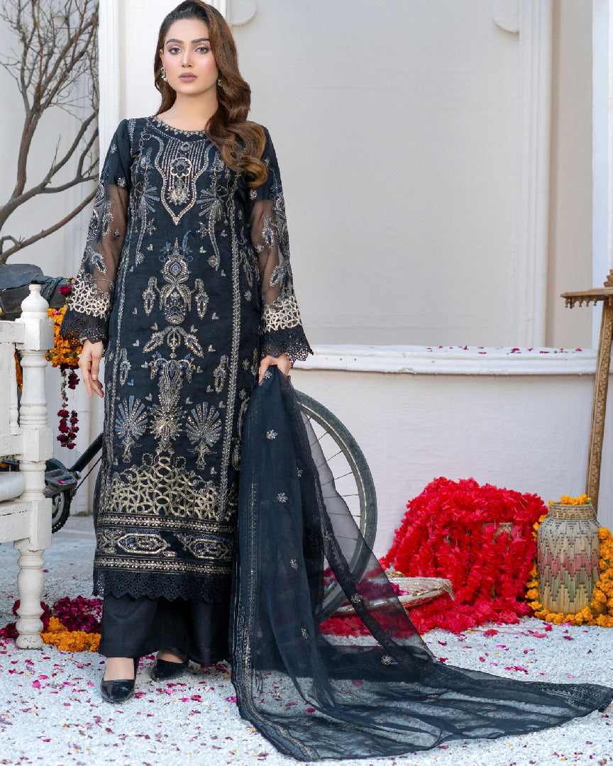 A woman wearing a black traditional dress with embroidered organza and silk details, including a dupatta and trousers.