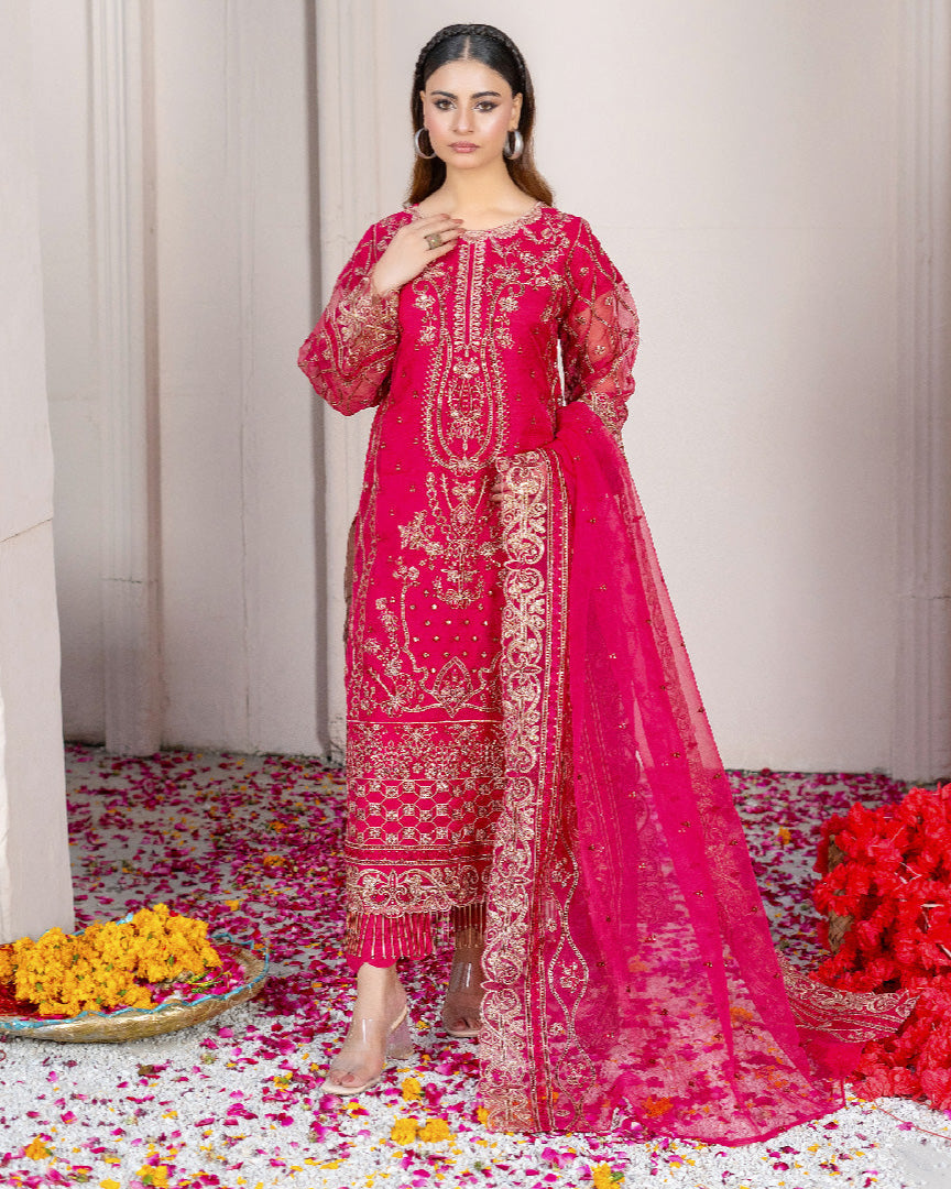 A woman wearing a traditional, embroidered pink dress with organza dupatta, consisting of a shirt, dupatta, and trousers.