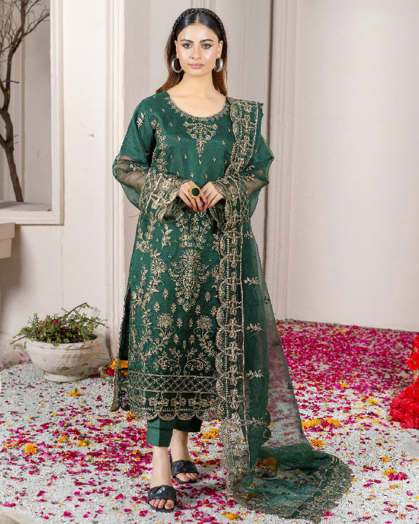 A woman wearing a green traditional dress with embroidered patterns and a dupatta.