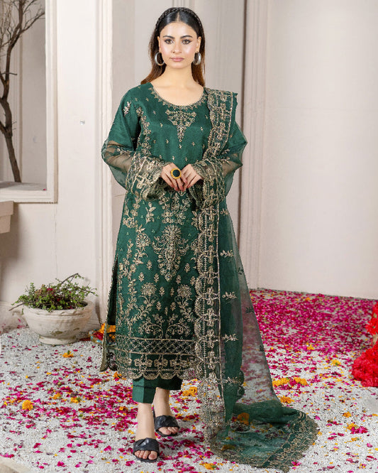A woman wearing a green traditional dress with embroidered patterns and a dupatta.